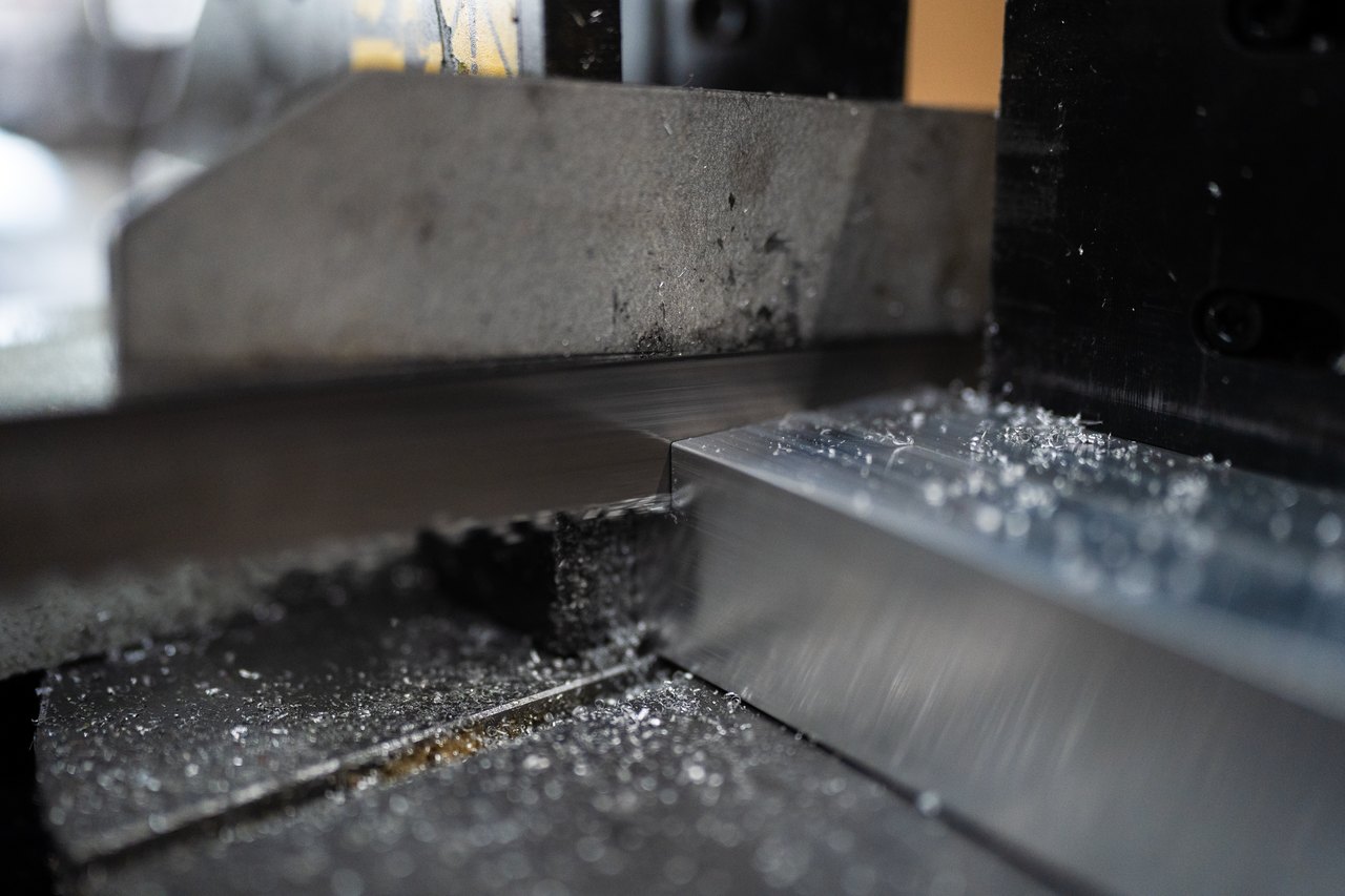 Ein Metallsägeblatt schneidet durch ein Aluminiumprofil, wobei Metallspäne entstehen.